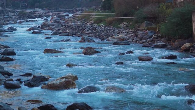 Slow motion shot of the Paravti River flowing in between mountains at Manikaran near Kasol in Himachal Pradesh, India. View of the Parvati river during the winter. Natural river in the mountains.	
