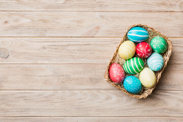 Multi colors Easter eggs in the woven basket on colored background . Pastel color Easter eggs. holiday concept with copy space