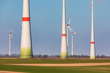 Massive towers of a wind farm dominate a rural landscape in Germany while needing a mind set change...