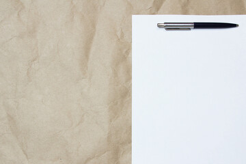 White empty sheet of A4 format with pen on a beige craft paper. Concept of analysis, study, attentive work. Stock photo with empty place for your text and design.