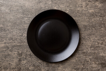 Top view of black plate on cement background. Empty space for your design