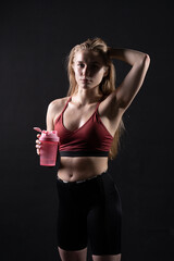 Fototapeta na wymiar Spotrsman her shaker pink holds in hand a girl in black background shaker pink black workout, In the afternoon gym lifestyle from young and training athlete, strong wellness. Care model