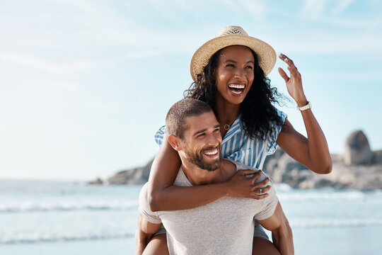 Theres always love in the air. Shot of a young man piggybacking his girlfriend at the beach.