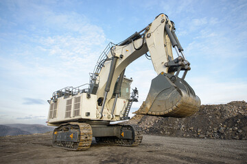 Big excavator in coal mine at cloudy day, low angle view