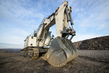 Big excavator in coal mine at cloudy day, low angle view