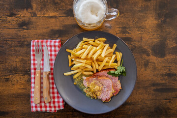 top view of a slice of roast pork with mustard on a plate with french fries