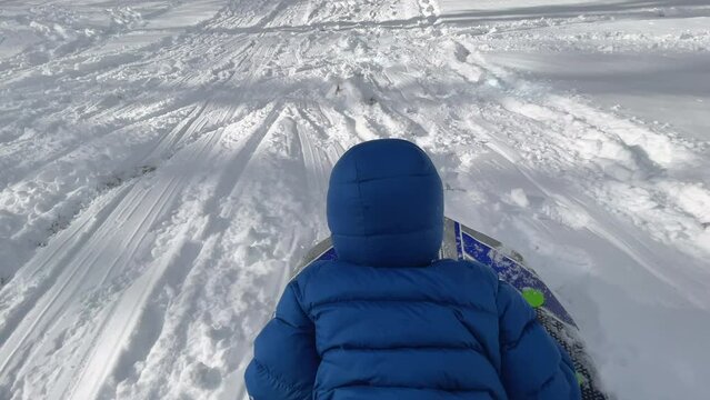 A child sleds headfirst down a snowy path