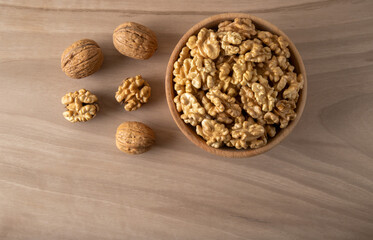 Bowl of walnuts and whole walnut kernels on wooden background,top view	