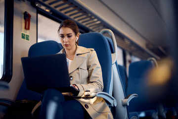 Young businesswoman works on laptop while commuting to work by train.