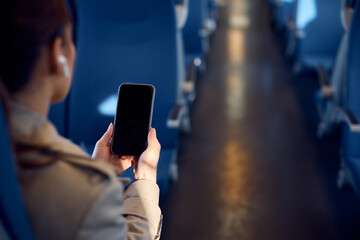 Close up of woman uses mobile phone while commuting by train.