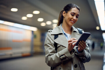 Happy passenger text messaging on her cell phone at subway station.