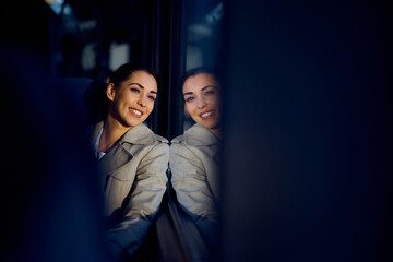 Young happy woman enjoys in train travel and looks through the window.