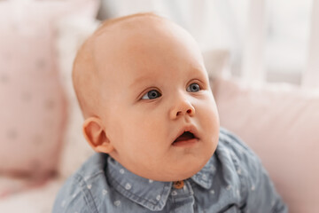 cute funny little baby girl sitting in a crib on a white cotton bed  in a bright children's room