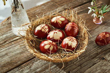 Homemade Easter eggs in a basket with snowdrops in spring