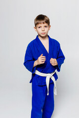 Young sports man in blue kimono for sambo, judo, posing on white background, looking straigh.