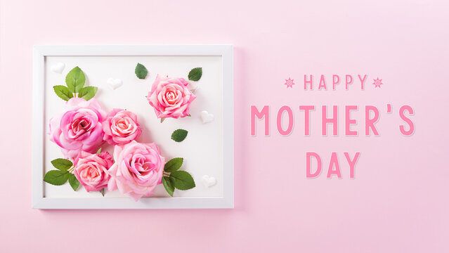 Happy Mother's Day decoration concept made from rose flower and picture frame with the text on pink pastel background.