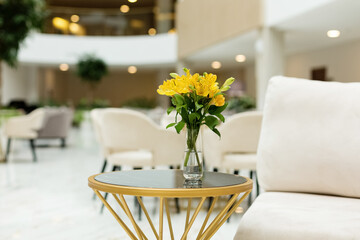 Interior of modern room with comfortable sofa and table with spring flowers