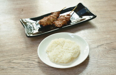 grilled pork in wooden stick eat with sticky rice on dish