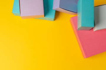 Colorful cardboard boxes on yellow background, copy space