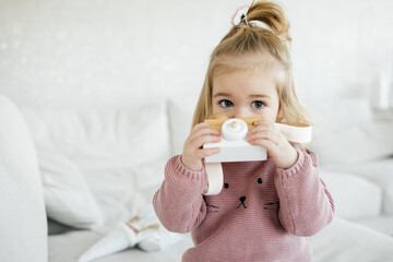 Small adorable girl holding wooden toy camera 