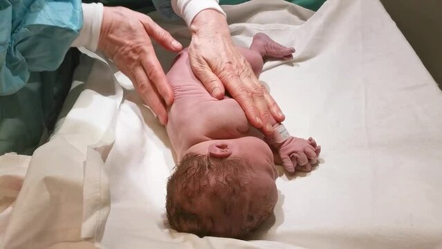 New born baby getting cleaned and checked by midwife after caesarean section. Cleaning amniotic fluid out of lungs. Surgery and hospital concept.