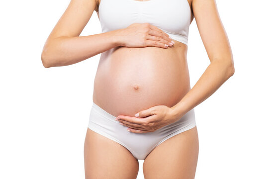 Young pregnant woman in swimsuit. Girl expecting a baby and touching her belly isolated on white background. Close-up image.