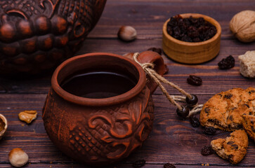 Country style. on a wooden table an hour in earthenware mugs and homemade hazelnut cookies with chocolate and raisins.