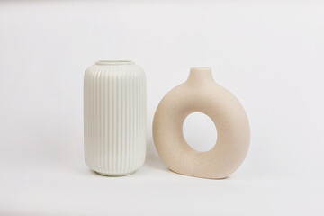 Beige and white vase of a beautiful flat round shape on a plain white background. The concept of Minimalism.