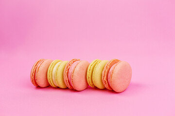 Obraz premium Close-up of a yellow almond cookie or macarons of pastel colors on a pink background with a place for writing and cutting. Minimalism.