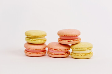 A tower of multicolored macaroons on a plain white background with a place for writing and cutting. Minimalism. Yellow, orange, pink. Beautiful cakes. Aesthetics.