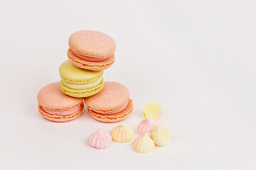 There are a lot of macaroons on a plain white background with a place for pastel-colored lettering. Stylish layout. Delicious cakes. Aesthetics.