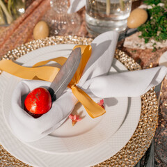 Festive Easter table setting. Funny Easter bunny made of egg and linen napkin on plate. Gray background.