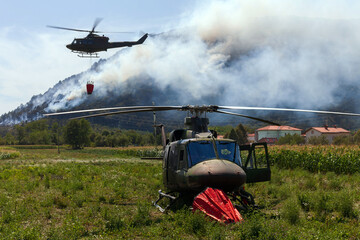 Fireman departments and Army Helicopters Working together fights a wild fire in the Background