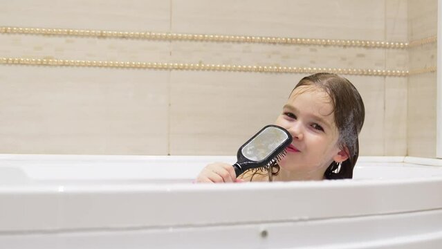 cheerful girl washes, plays and sings into comb like microphone in bathroom