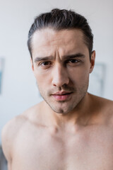 portrait of shirtless man looking at camera at home.