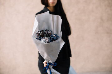 Very nice young woman holding beautiful mono bouquet of fresh blue dyed carnations, cropped photo,...