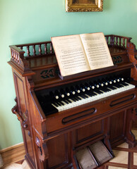 An old brown piano with an open book with scores. Vintage household items. Historical value.
