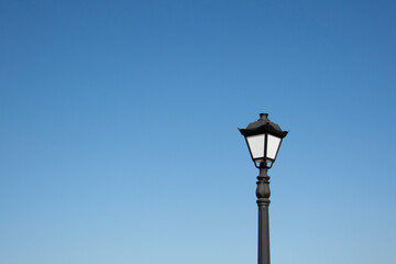 Fototapeta na wymiar An antique lantern on a blue sky background. Vintage street lamp in the daytime. 