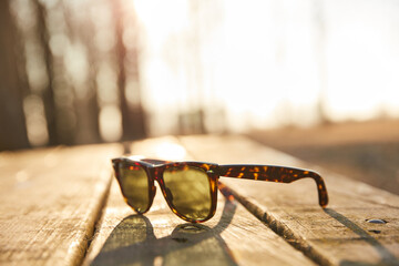 sunglasses on the vintage wooden table on sunrise with blurred background