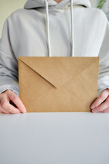 Envelope in hands on a light background. New mail, message. Postal service. The person wants to...