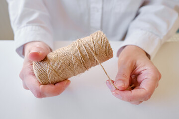 A skein of jute twine in the hands on a white background. Natural rope for packaging and...