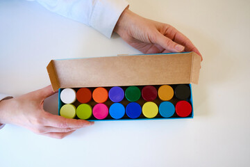 The girl holds a box with colored paints on a light background. Creative background. Paint for...