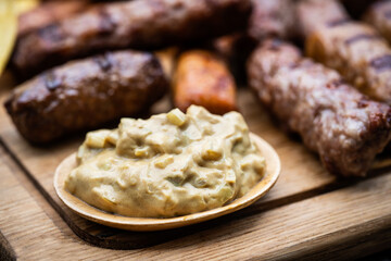 Gegrillte Cevapcici mit Zwiebelsenf auf einem Holzbrett