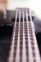 Vertical shot of the neck of a black acoustic guitar with five strings