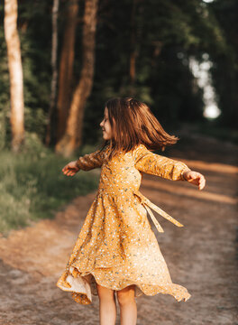 Girl running on the forest  on summer sunset. Beautiful little kid girl dancing. Summer fun outdoors.