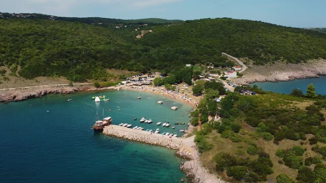 Aerial view of packed Risika Beach on Krk island in Croatia with a pirate ship in summertime