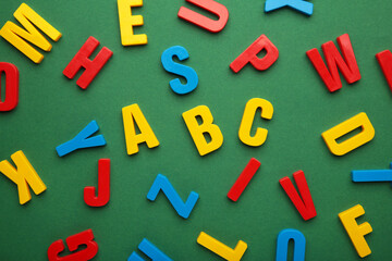 Magnetic plastic alphabet letters on green background.