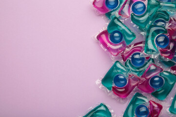 Laundry capsule detergent pods for washing clothes on purple background.