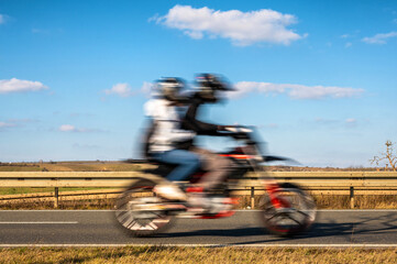 Motorradfahrer und Sozius auf einem Motorrad mit blauem Himmel zum Thema Transport und Freiheit