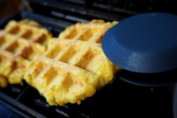 side view of two fresh Belgian waffles made from corn flour, eggs and pumpkin lying in a waffle...